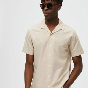Camisa de manga corta y cuello cubano, confeccionada en lino y algodón, corte recto y color arena