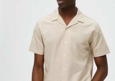 Camisa de manga corta y cuello cubano, confeccionada en lino y algodón, corte recto y color arena